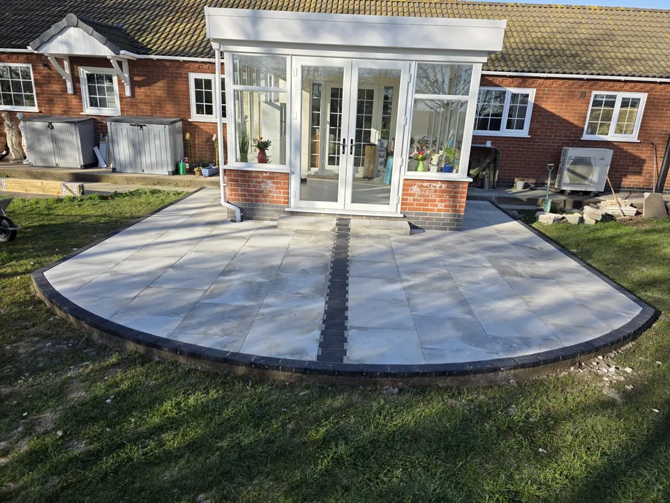 Stone patio with a dark border outside a brick home